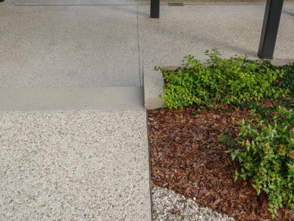 Dettaglio del cortile interno con pavimentazione in Italian Terrazzo Ghiaino Lavato Isoplam e aiuole verdi integrate per aziende