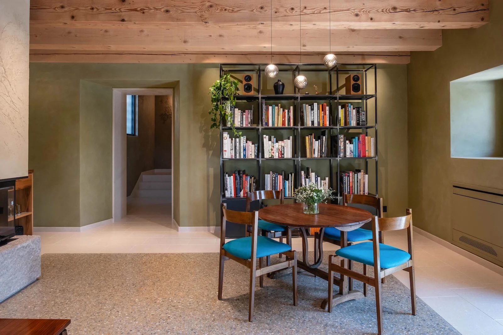 Pavimento in graniglia effetto maxi veneziana Terrazzoverlay XL nella zona living di un B&B dal design contemporaneo con libreria e soffitto in legno
