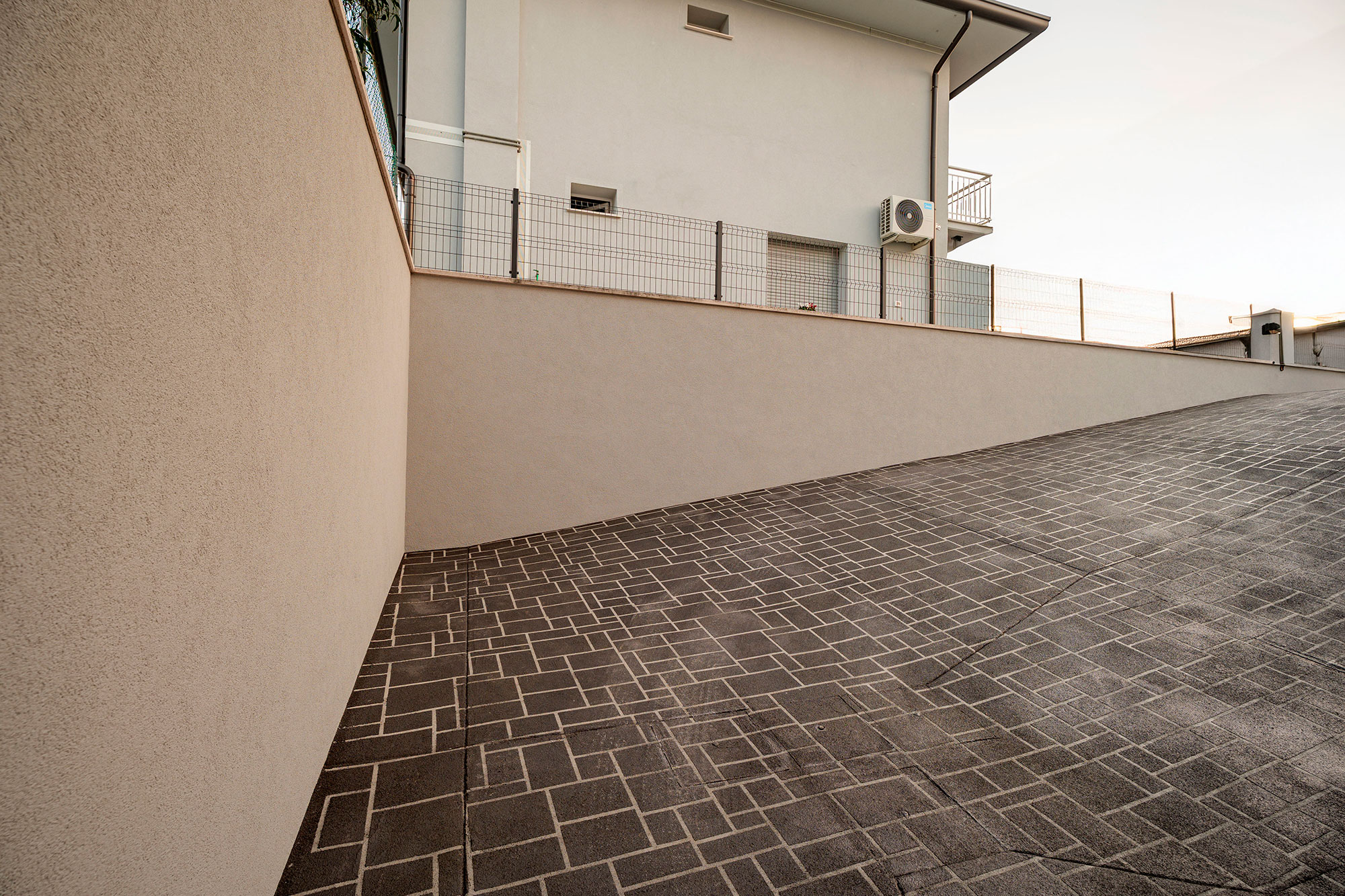 Pavimentazione esterna in cemento spruzzato Plam Spray Isoplam con disegno geometrico personalizzato, finitura idrorepellente per superfici carrabili e pedonali.