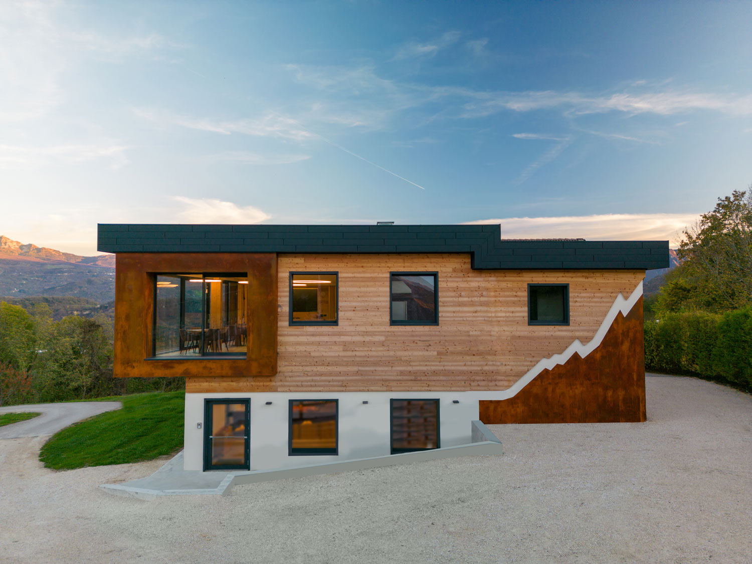 Edificio contemporaneo immerso nel verde con rivestimento effetto corten e facciata ventilata in legno