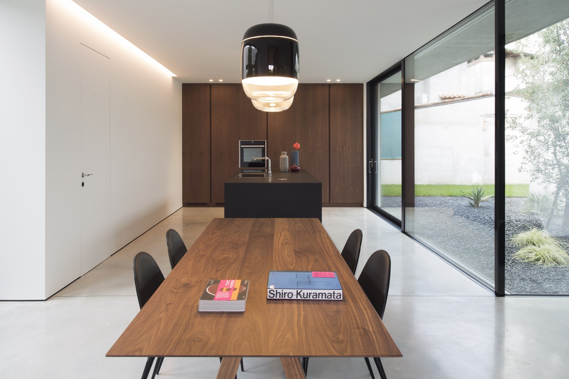 Pavimento Deco Nuvolato Isoplam in cucina open space con isola nera, mobili in legno e tavolo da pranzo